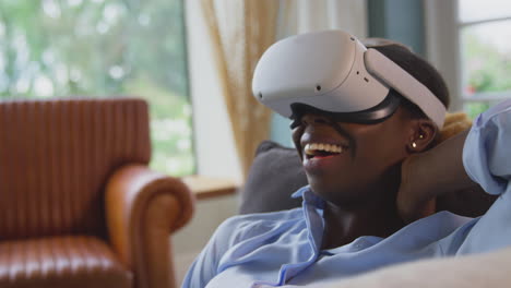 Woman-Relaxing-Lying-On-Sofa-At-Home-Wearing-VR-Headset-And-Interacting-With-AR-Technology