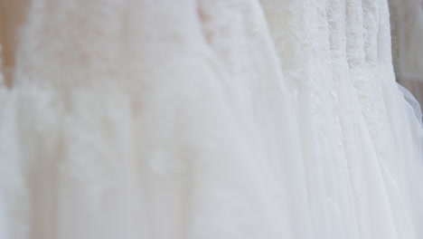Close-Up-Of-Beautiful-Bridal-Wedding-Dresses-Hanging-On-Rail-In-Shop