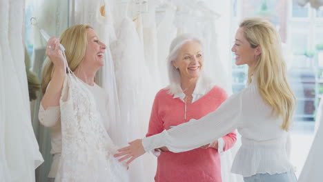 Verkäuferin-Mit-Erwachsener-Tochter-Hilft-Mutter-Bei-Der-Auswahl-Eines-Hochzeitskleides-Im-Brautmodengeschäft