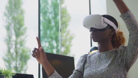 Woman-Working-From-Home-Office-At-Desk-Wearing-VR-Headset-Interacting-With-AR-Technology