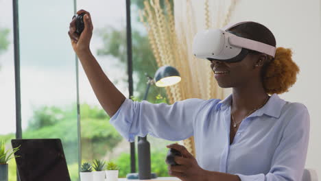 Woman-Working-From-Home-Office-With-Controllers-Wearing-VR-Headset-Interacting-With-AR-Technology