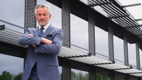 Portrait-Of-Serious-Senior-Businessman-CEO-Chairman-Standing-Outside-Modern-Office-Building