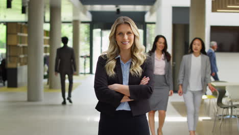Portrait-Of-Mature-Businesswoman-CEO-Chairman-Standing-In-Lobby-Of-Busy-Modern-Office-Building