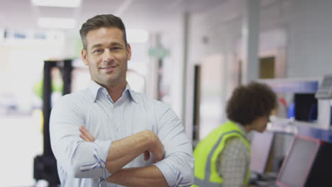 Portrait-Of-Smiling-Male-Manager-In-Busy-Logistics-Distribution-Warehouse