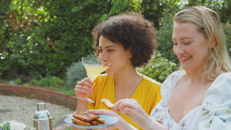 Drei-Freundinnen-Sitzen-Draußen-Im-Sommergarten-Zu-Hause,-Trinken-Cocktails-Und-Essen
