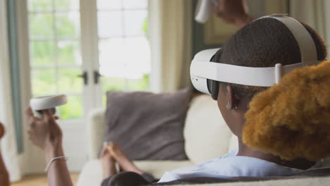 Woman-Lying-On-Sofa-At-Home-Wearing-VR-Headset-With-Controllers-And-Interacting-With-AR-Technology