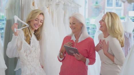 Verkäuferin-Mit-Mutter-Hilft-Erwachsener-Tochter-Bei-Der-Auswahl-Eines-Hochzeitskleides-Im-Brautmodengeschäft