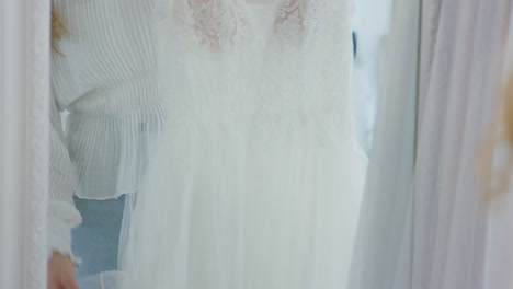 Woman-Choosing--Wedding-Dress-In-Bridal-Store-Looking-in-Mirror