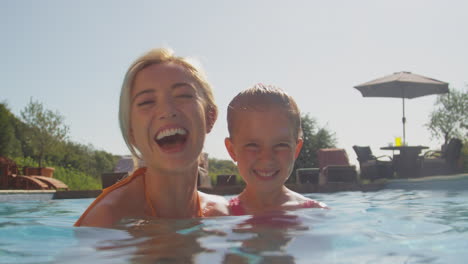 Portrait-Of-Mother-And-Daughter-Having-Fun-In-Swimming-Pool-On-Family-Summer-Holiday