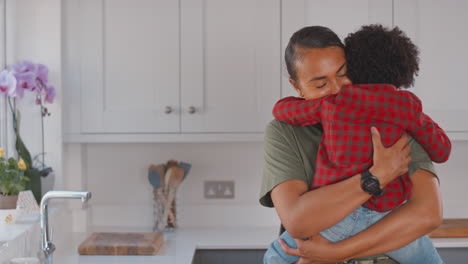 Loving-Mother-Carrying-And-Hugging-Son-At-Home-In-Family-Kitchen