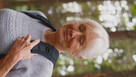 Active-Retired-Senior-Woman-Walking-In-Woodland-Countryside-Wearing-Backpack-Breathing-Fresh-Air