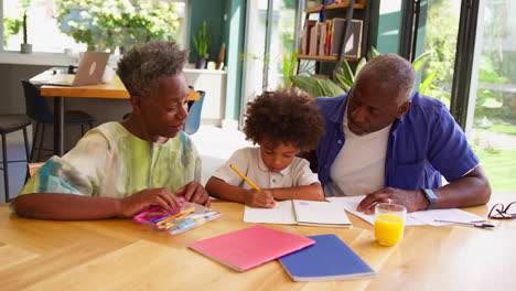 Mehrgenerationenfamilie-Mit-Großeltern,-Die-Dem-Enkel-Zu-Hause-Bei-Den-Schularbeiten-Helfen