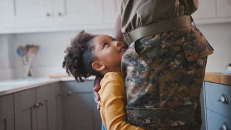 Close-Up-Of-Daughter-Hugging-Legs-Of-Army-Father-In-Uniform-Home-On-Leave-In-Family-Kitchen