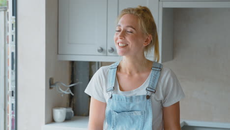 Portrait-Of-Smiling-Woman-Wearing-Dungarees-Renovating-Kitchen-At-Home