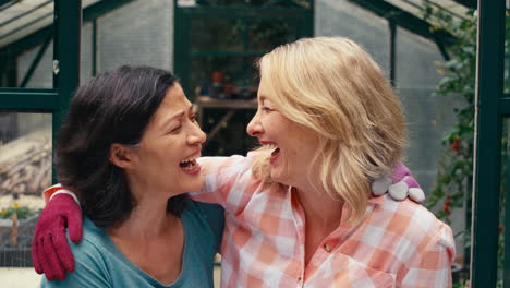 Portrait-Of-Loving-Same-Sex-Mature-Female-Couple-Hugging-As-They-Garden-In-Greenhouse-Together