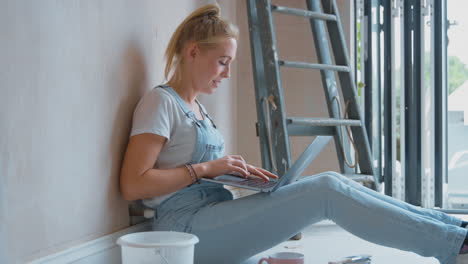 Woman-Renovating-Room-At-Home-Sits-On-Floor-With-Laptop-Taking-A-Break-From-Decorating