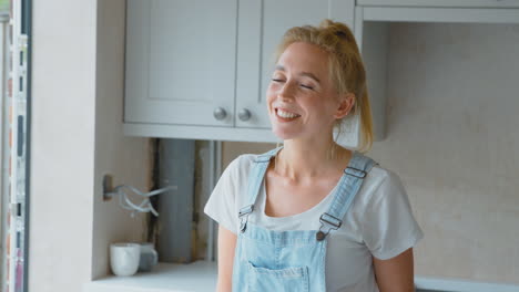 Retrato-De-Una-Mujer-Sonriente-Vistiendo-Petos-Renovando-La-Cocina-En-Casa