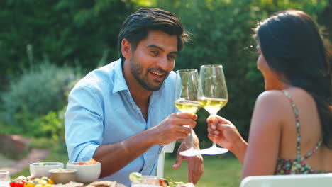Couple-Eating-Outdoor-Meal-And-Drinking-Wine-In-Garden-At-Home-Together