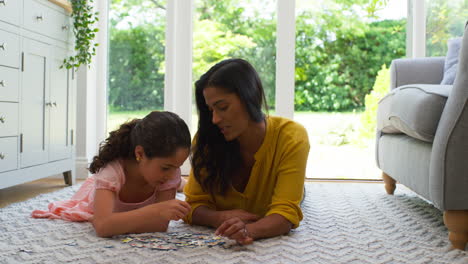 Mother-And-Daughter-At-Home-Lying-On-Floor-In-Lounge-Doing-Jigsaw-Puzzle-Together
