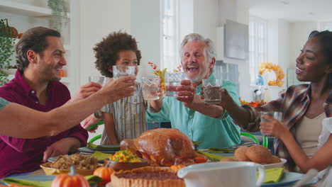 Mehrgenerationenfamilie-Feiert-Thanksgiving-Zu-Hause,-Isst-Essen-Und-Jubelt-Mit-Wasser