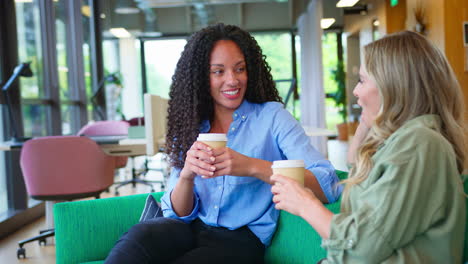 Mujeres-Empresarias-Con-Café-Teniendo-Una-Reunión-Informal-En-La-Zona-De-Descanso-De-La-Oficina-Moderna