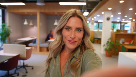 POV-Selfie-Portrait-Of-Businesswoman-Walking-Through-Modern-Office-Talking-To-Mobile-Phone-Camera