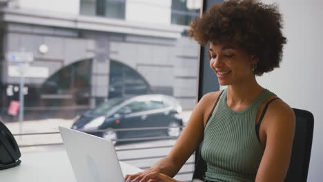 Geschäftsfrau-Im-Modernen-Büro,-Die-Am-Laptop-Arbeitet,-Mit-Belebter-Straßenszene-Im-Hintergrund