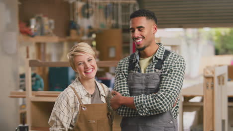 Portrait-Of-Smiling-Male-And-Female-Apprentices-Working-As-Carpenters-In-Furniture-Workshop