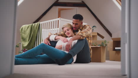 Loving-Couple-Expecting-Baby-Hugging-In-Nursery-Of-New-Home-Together-With-Moving-In-Boxes