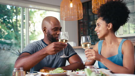 Couple-Sitting-Around-Table-At-Home-Doing-Cheers-With-Wine-Before-Meal