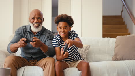 Großvater-Und-Enkel-Sitzen-Zu-Hause-Auf-Dem-Sofa-Und-Spielen-Gemeinsam-Videospiele
