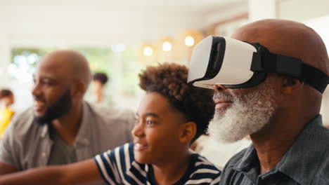 Grandfather-Wearing-VR-Headset-As-Multi-Generation-Male-Family-Sit-On-Sofa-At-Home-Together