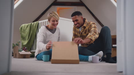 Couple-Expecting-Baby-Eating-Pizza-In-Nursery-Of-New-Home-Together-With-Moving-In-Boxes