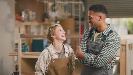Portrait-Of-Smiling-Male-And-Female-Apprentices-Working-As-Carpenters-In-Furniture-Workshop