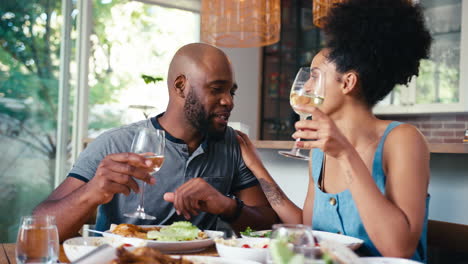 Couple-Sitting-Around-Table-At-Home-Enjoying-Meal-With-Wine-Together