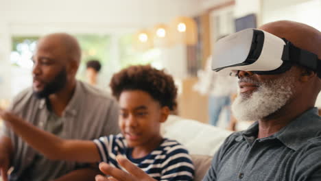 Großvater-Trägt-VR-Headset,-Während-Eine-Männliche-Mehrgenerationenfamilie-Zu-Hause-Zusammen-Auf-Dem-Sofa-Sitzt