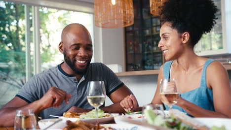 Couple-Sitting-Around-Table-At-Home-Enjoying-Meal-With-Wine-Together