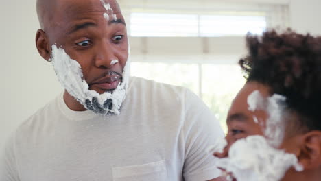 Close-Up-Of-Father-And-Son-At-Home-Having-Fun-Playing-With-Shaving-Foam-In-Bathroom-Making-A-Mess