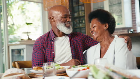 Liebendes-älteres-Paar-Sitzt-Zu-Hause-Am-Tisch-Und-Genießt-Das-Gemeinsame-Essen