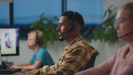 Business-Team-Wearing-Headsets-Working-Late-At-Customer-Support-Centre