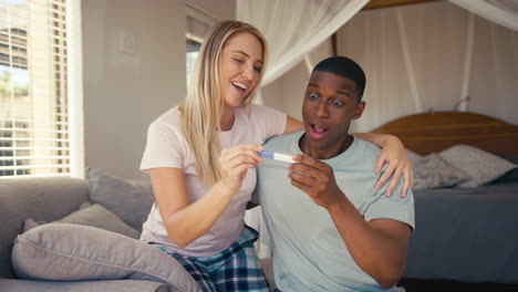 Aufgeregtes-Paar-Im-Schlafzimmer-Zu-Hause-Feiert-Positives-Schwangerschaftstestergebnis