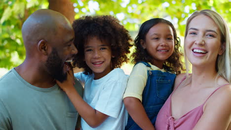 Portrait-Of-Multi-Racial-Family-Standing-In-Garden-Smiling-At-Camera