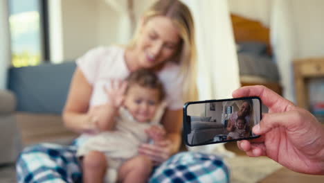 Father-Recording-Video-Of-Mother-And-Son-Sitting-On-Sofa-At-Home-On--Mobile-Phone