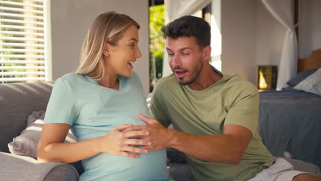 Couple-With-Pregnant-Woman-In-Bedroom-At-Home-With-Man-Feeling-Baby's-Heartbeat