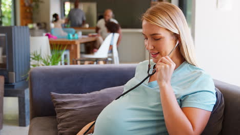 Mujer-Embarazada-En-Casa-Escuchando-Los-Latidos-Del-Corazón-Del-Bebé-Con-Estetoscopio