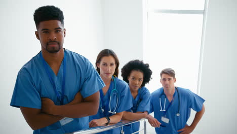 Portrait-Of-Serious-Multi-Cultural-Medical-Team-Wearing-Scrubs-Standing-On-Stairs-In-Hospital