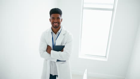Portrait-Of-Smiling-Male-Doctor-Wearing-White-Coat-Holding-Digital-Tablet-On-Stairs-In-Hospital