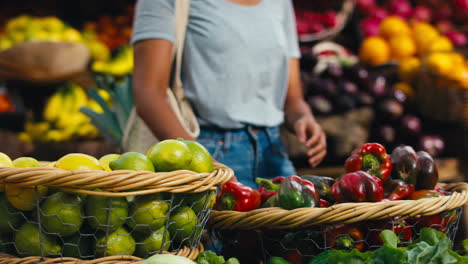 Close-Up-Female-Customer-At-Market-Stall-Choosing-Bell-Peppers-And-Lemons