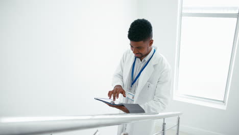 Männlicher-Arzt-Im-Weißen-Kittel-Mit-Digitalem-Tablet,-Der-Patientennotizen-Auf-Der-Treppe-Im-Krankenhaus-überprüft