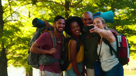 Group-Of-Friends-With-Backpacks-Posing-For-Selfie-On-Mobile-Phone-On-Vacation-Hiking-In-Countryside